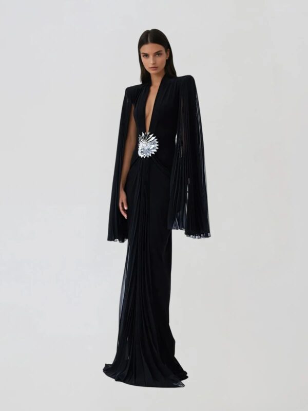 Rochie lungă de seară neagră cu decolteu adânc, mâneci tip capă plisate și broșă florală argintie