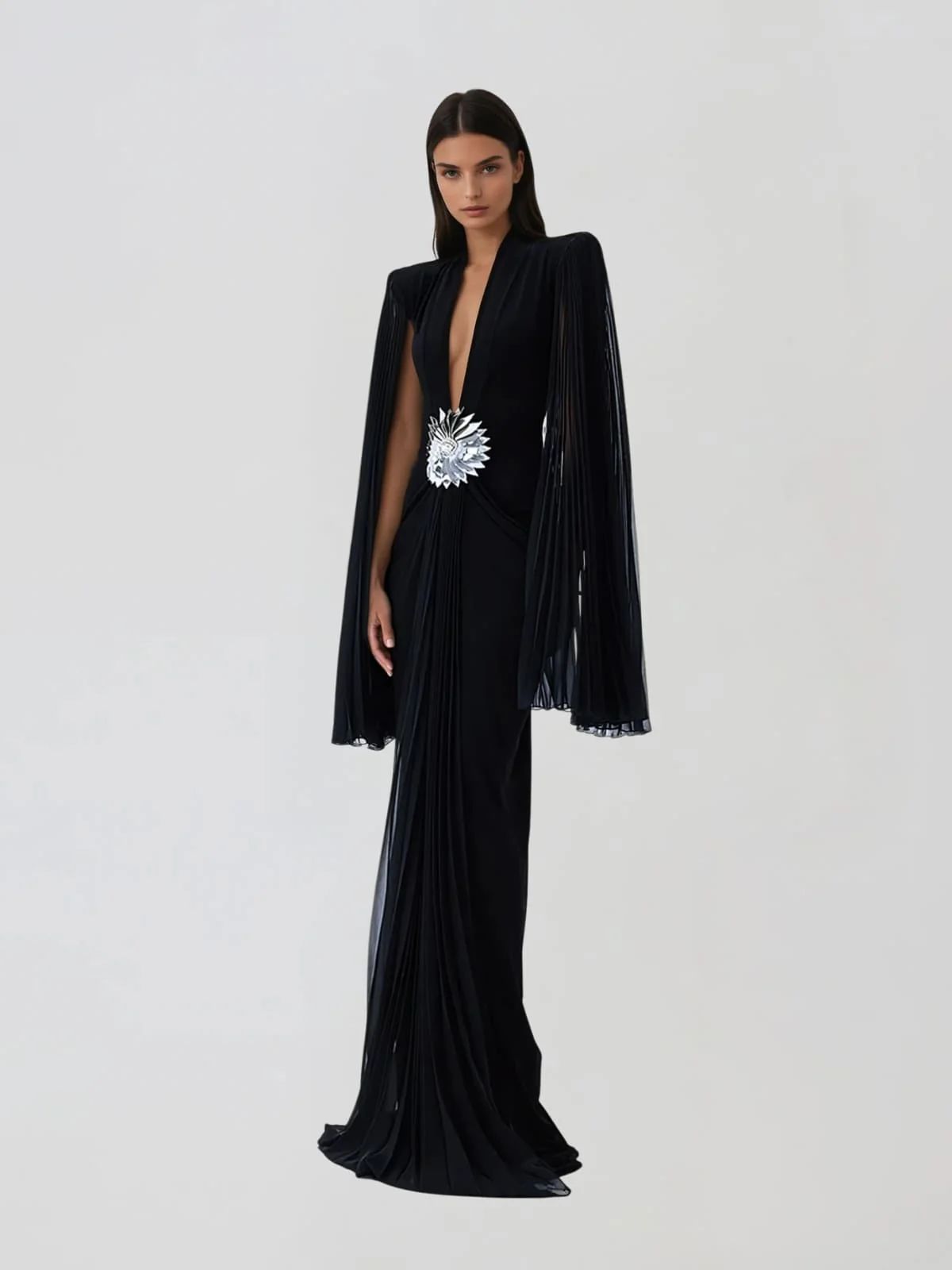 Rochie lungă de seară neagră cu decolteu adânc, mâneci tip capă plisate și broșă florală argintie